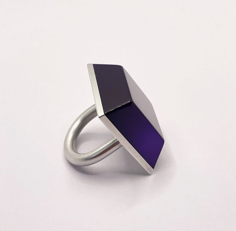 Anello grande ma leggero, composto da una base in alluminio e una finta pietra in resina viola, di forma squadrata simile ad una piramide bassa