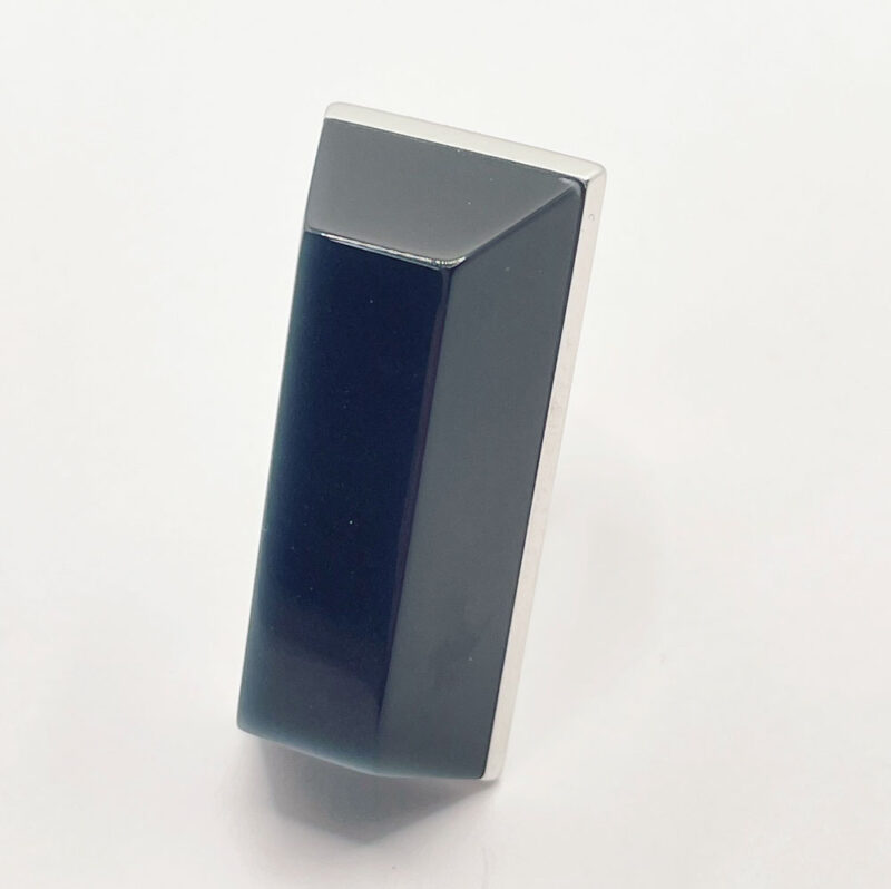Anello grande ma leggero, composto da una base in alluminio e una finta pietra in resina color grigio tendente al blu navy, di forma squadrata simile ad una piramide bassa