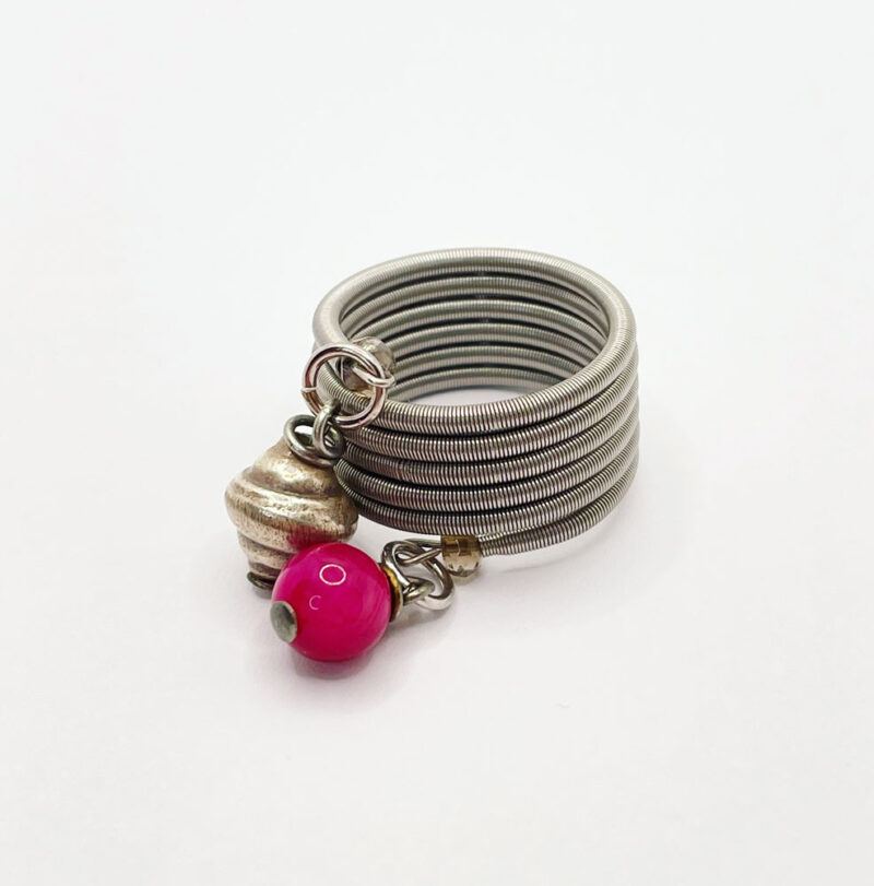 Anello fatto con una molla in acciaio a spirale e due ciondoli in alluminio e quarzo color magenta